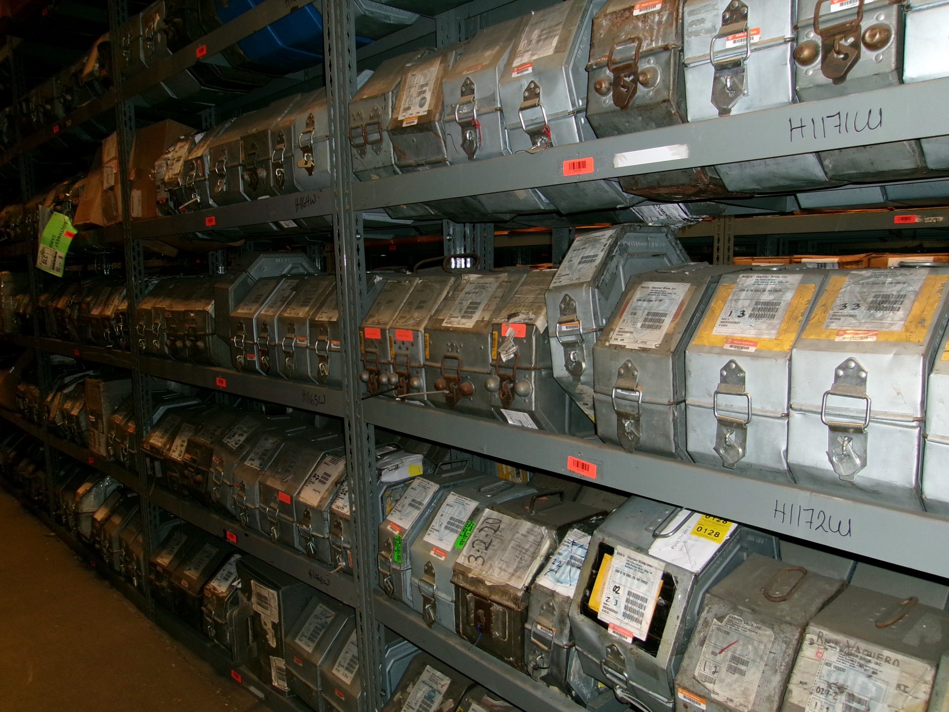 Distribution Rows of metal containers with labels and locks are stored on industrial shelves in a warehouse or archive.