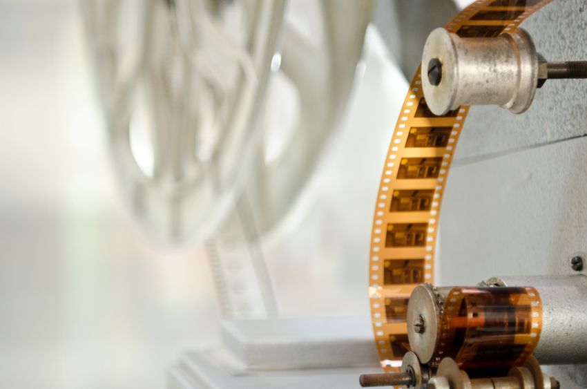film projector Close-up of a film reel and filmstrip threaded through a vintage film projector.